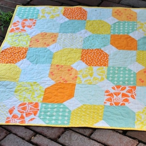 May include: A yellow, orange, and turquoise patchwork quilt with a white background. The quilt is made of various fabrics with different patterns, including polka dots, flowers, and geometric shapes.
