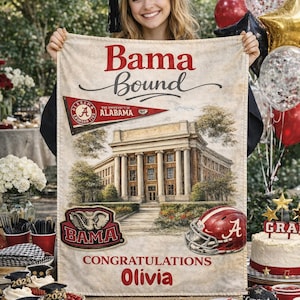 Könnte beinhalten: Eine Abschlussdecke mit dem Text "Bama Bound" und "Herzlichen Glückwunsch Olivia". Die Decke zeigt das Logo der University of Alabama, einen Footballhelm und eine Gebäudeillustration. Die Szene umfasst Cupcakes, Luftballons und einen Kuchen.