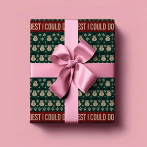 May include: A wrapped gift with a green and red patterned paper featuring snowmen and snowflakes. The text "BEST I COULD DO" is printed on the paper. A pink satin ribbon and bow are tied around the gift.