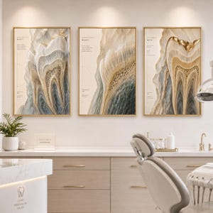 May include: Three framed abstract art pieces with gold frames. The art features a tooth-like design with beige, gold, and blue tones. Each piece has text at the top left. The art is displayed in a dental office setting.