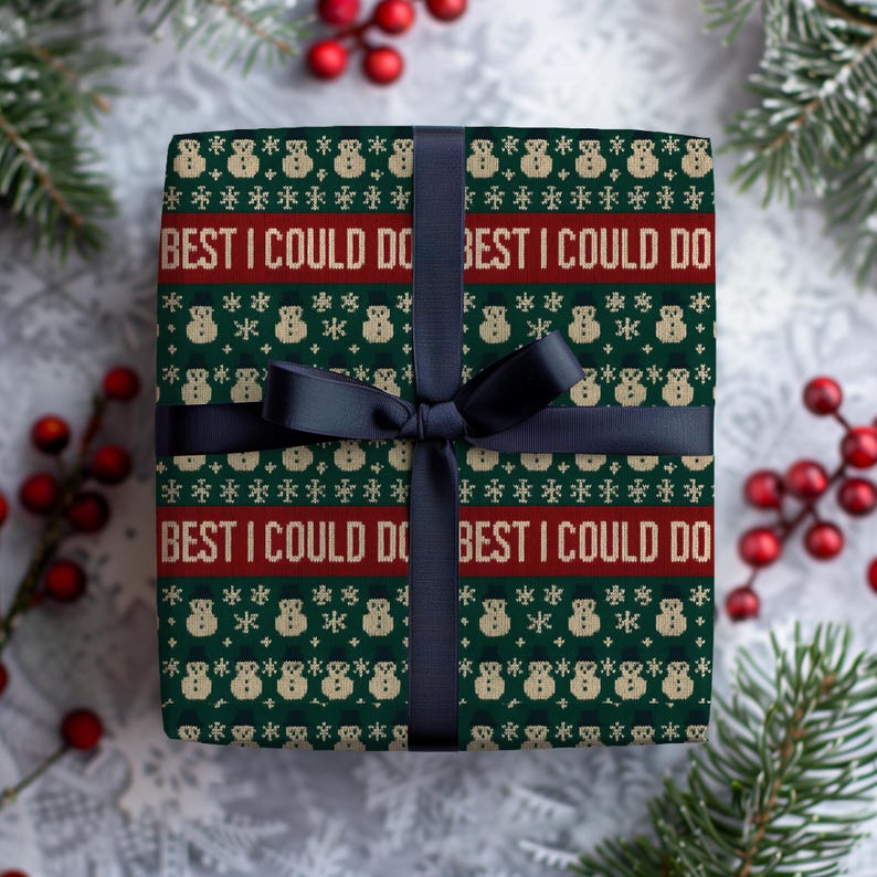 May include: A wrapped gift with a dark green and red patterned paper featuring snowmen and snowflakes. The text "BEST I COULD DO" is printed on the paper. A black ribbon and bow secure the gift, perfect for the holiday season.