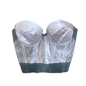May include: A silver strapless corset with a dark green elastic band at the bottom.