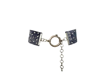 May include: A silver chain bracelet with two black fabric sections, each with silver studs. The bracelet has a silver clasp.