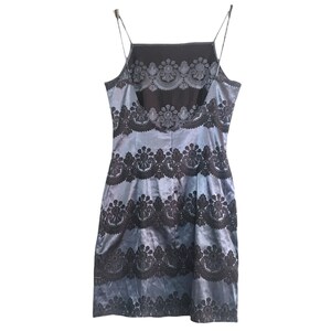 Puede incluir: Un vestido azul y negro sin mangas con un patr&oacute;n de encaje. El vestido tiene un corpi&ntilde;o ajustado y una falda fluida.