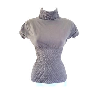 May include: A grey short-sleeved top with a high, ribbed turtleneck. The bodice features a textured, diamond-patterned design that cinches at the waist. The top is made of a soft, form-fitting material.