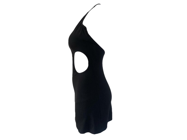 May include: A black halter dress with a side cutout. The dress is sleeveless and has a fitted silhouette. The cutout is a large oval shape. The dress is made of a smooth, solid fabric.