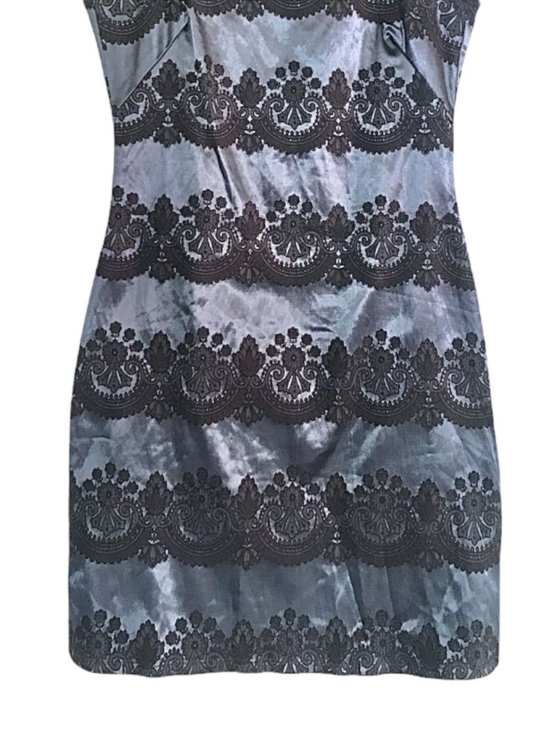 Puede incluir: Un vestido sin mangas con fondo azul y ribete de encaje negro. El ribete de encaje es un patr&oacute;n repetido de dise&ntilde;os florales y paisley.