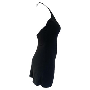 May include: A black halter dress. The dress is sleeveless with a halter neckline and a fitted silhouette. The fabric appears to be a smooth, solid color. The dress is designed to be worn without sleeves.