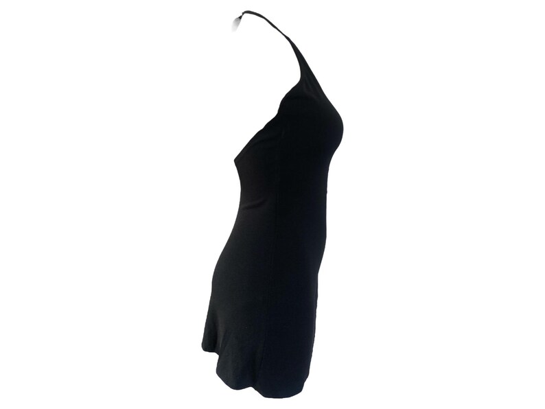 May include: A black halter dress. The dress is sleeveless with a halter neckline and a fitted silhouette. The fabric appears to be a smooth, solid color. The dress is designed to be worn without sleeves.