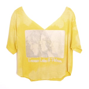 May include: Yellow t-shirt with a faded image of two people and the text "Emerson, Lake & Palmer" printed on the front.