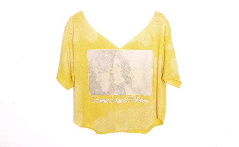 May include: Yellow t-shirt with a faded image of two people and the text "Emerson, Lake & Palmer" printed on the front.