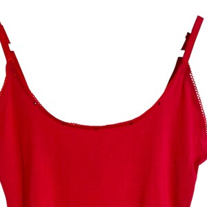 May include: A red tank top with thin straps and a scalloped trim around the neckline.