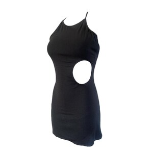 May include: A black mini dress with a halter neckline and a side cutout. The dress is sleeveless and form-fitting, showcasing a sleek and modern design. The dress is made of a soft, stretchy material.
