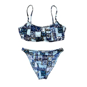 Puede incluir: Un top y una parte inferior de bikini con estampado azul y blanco. El top tiene tirantes ajustables y un escote redondo. La parte inferior es de estilo de corte alto.