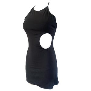 May include: A black mini dress with a halter neckline and a large circular cutout on the side. The dress is sleeveless and form-fitting, made of a smooth, solid fabric. The dress is designed to be worn as a party dress.