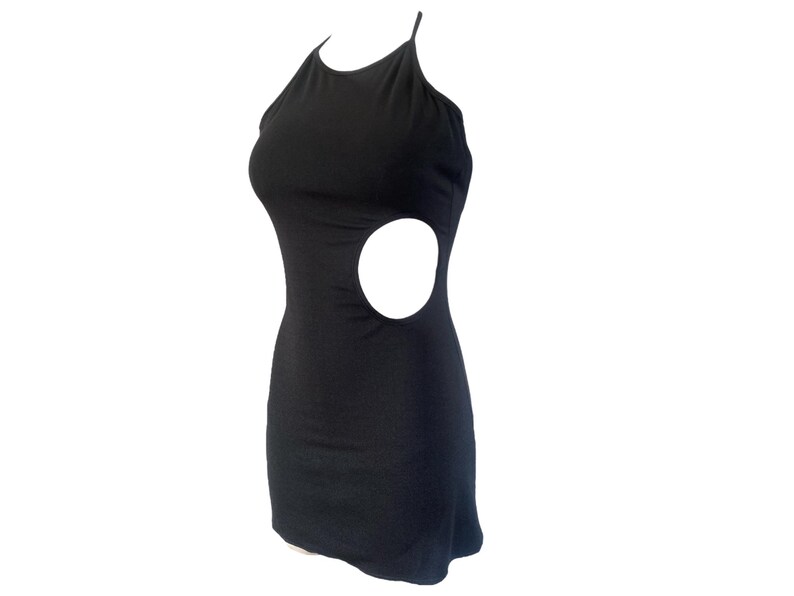 May include: A black mini dress with a halter neckline and a large circular cutout on the side. The dress is sleeveless and form-fitting, made of a smooth, solid fabric. The dress is designed to be worn as a party dress.