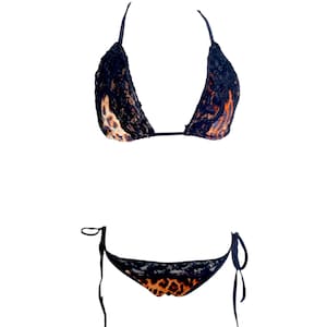 May include: A two-piece bikini set featuring a halter top and tie-side bottoms. The bikini has a black lace overlay with a leopard print fabric underneath. The set is designed for swimwear.