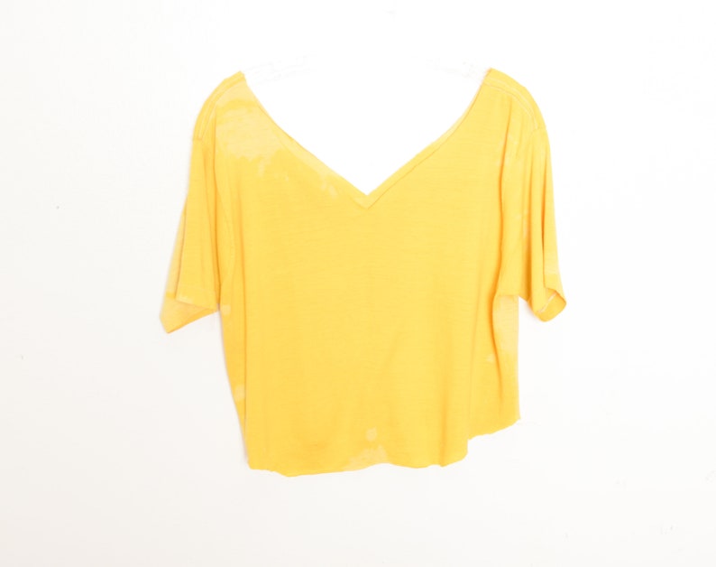 May include: A yellow short-sleeved v-neck t-shirt with a slightly cropped hem.