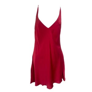 May include: A short, sleeveless slip dress in a solid deep red color. The garment features a V-neckline and thin spaghetti straps, with a smooth, slightly reflective fabric finish that falls to a straight hemline above the knee.