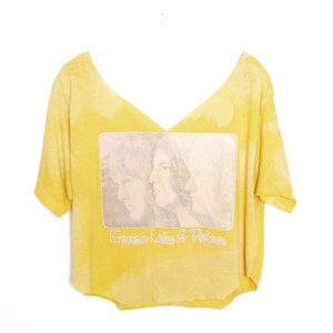 May include: Yellow cropped t-shirt with a faded image of three people and the text "Emerson, Lake & Palmer".