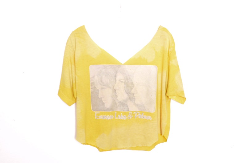 May include: Yellow cropped t-shirt with a faded image of three people and the text "Emerson, Lake & Palmer".