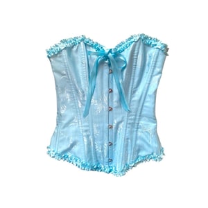 May include: A pale blue corset with a floral design. The corset features a frilled trim along the top and bottom. A light blue ribbon is tied in a bow at the centre, and it fastens with small silver-coloured clasps.