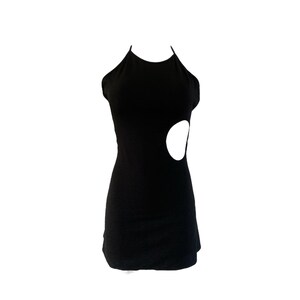 May include: A black halter dress with a unique design. The dress features a fitted silhouette and a large, circular cutout on the side. The dress is made of a smooth, solid black fabric.