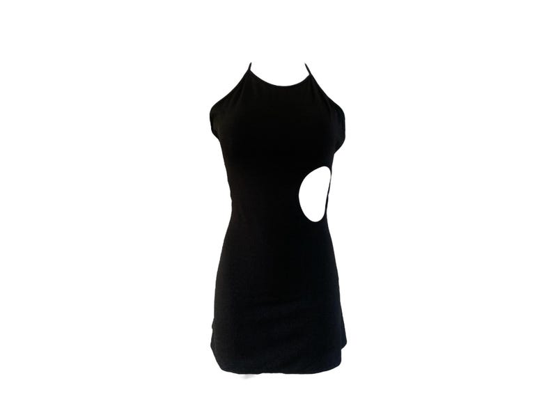 May include: A black halter dress with a unique design. The dress features a fitted silhouette and a large, circular cutout on the side. The dress is made of a smooth, solid black fabric.