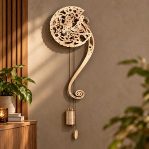 May include: A light-coloured wooden wall clock featuring an intricate, open-work gear mechanism in a circular upper section. A long, curved, decorative wooden arm extends downwards, supporting a cylindrical weight and a small pendulum hanging by thin black cords.