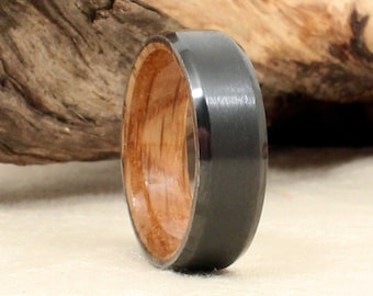 May include: A black and brown wooden ring with a beveled edge. The ring is made of black tungsten carbide and wood.
