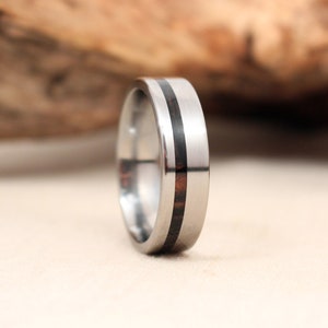 May include: A silver ring with a thin black inlay band.