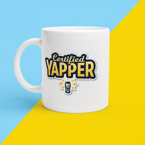 Op de afbeelding: Een witte keramische mok met de tekst Certified YAPPER in dikke gele letters met een donkerblauwe omlijning. Onder de tekst staat een kleine afbeelding van een blauwe klaptelefoon omringd door vier gele sterpictogrammen op de voorzijde.