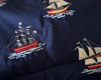 May include: Dark blue fabric featuring a repeating pattern of red and yellow sailboats. The sailboats have white sails and are shown sailing on blue waves. The fabric has a nautical theme.