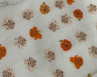 May include: A white fabric featuring a repeating pattern of small roses in shades of orange, brown, and light pink. The text "heather ross for Spoonflower" is printed in a yellow banner near the top edge of the textile material.