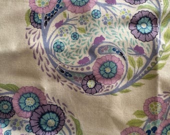 May include: Cream fabric with a repeating floral design. The pattern showcases stylised flowers in purple, light blue, and pink, with green leaves and stems. The design is arranged in circular motifs.