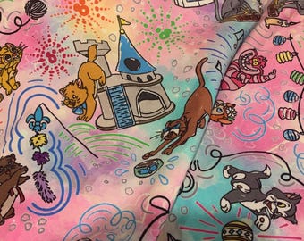 May include: Fabric featuring a colorful tie-dye background in shades of pink, blue, and yellow. The pattern displays various cartoon cats, a castle, a circus tent, fireworks, yarn balls, and decorative string lights in a whimsical, repeating design.