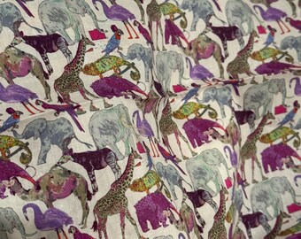 May include: Cream-coloured fabric featuring a repeating pattern of animals such as elephants, giraffes, parrots, and flamingos. The animals are in shades of purple, green, grey, and brown. The fabric has a slightly creased texture.