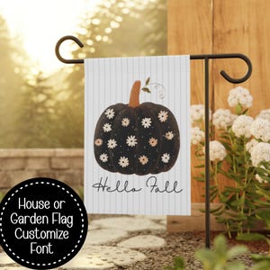 May include: A vertical garden flag featuring a black pumpkin decorated with small white and light orange daisy flowers. The background is white with thin vertical grey stripes. The text "Hello Fall" is printed in black cursive script below.