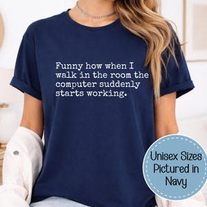 May include: A navy blue short-sleeved t-shirt featuring white text that reads: Funny how when I walk in the room the computer suddenly starts working. A circular badge in the bottom right corner contains the text: Unisex Sizes Pictured in Navy.