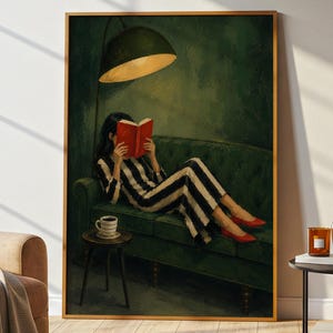 May include: A framed art print shows a person in a black and white striped outfit reading a red book on a green sofa. A lamp illuminates the scene, with a coffee cup on a side table. The person wears red shoes, adding a pop of colour.
