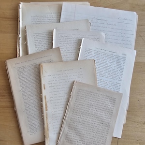 Può includere: Una collezione di vecchi documenti, tra cui pagine di libri e fogli sparsi, disposti su una superficie di legno chiaro. I documenti presentano testo in diverse lingue, con segni visibili di usura, che indicano età e utilizzo.