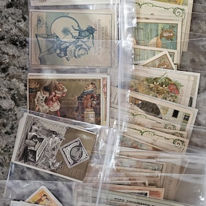 May include: A collection of vintage trading cards in plastic sleeves. The cards feature colorful illustrations and text, with some cards displaying the word "PORTO". The cards are from various brands and eras, showcasing a variety of themes and designs.