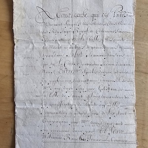 May include: Aged, handwritten document with faded ink on aged paper. The document features elaborate cursive script, with visible folds and wear. The text appears to be in French, with a decorative initial letter at the top. The paper has a yellowed hue.