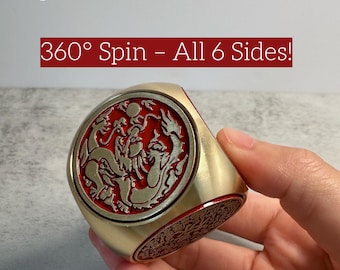 May include: A gold-colored, six-sided spinning ring with a red and gold dragon design. The ring has the text "Spin for Focus & Peace" and "360° Spin - All 6 Sides!" on the image.