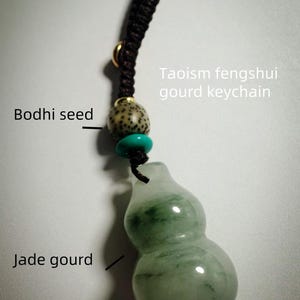 Puede incluir: Un llavero de calabaza fengshui taoísta. El llavero presenta un colgante de calabaza de jade con vetas verdes, una cuenta de semilla de Bodhi y una cuenta turquesa. El llavero está sujeto a un cordón trenzado marrón oscuro.
