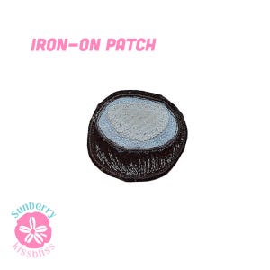 Könnte beinhalten: Ein Aufbügler mit einem kreisförmigen Design, das einen dunkelbraunen Außenrand und eine hellblaue Mitte aufweist. Der Text IRON-ON PATCH ist in Pink über dem Aufbügler gedruckt, und ein pinkes Blumenlogo mit Sunberry kissbliss befindet sich darunter.