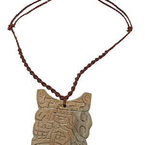 May include: A carved pendant necklace with a brown cord. The pendant is a light brown color and features an abstract design with carved lines and shapes. The cord is knotted and adjustable.
