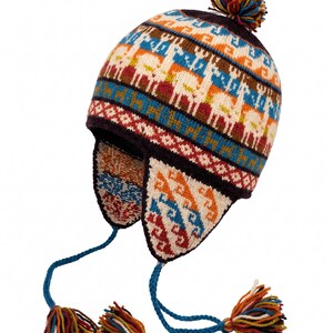 May include: A knit earflap hat featuring a colorful pattern of llamas and geometric shapes in shades of orange, blue, white, and brown. The hat includes braided blue ties with multi-colored tassels and a matching pom-pom on the crown.