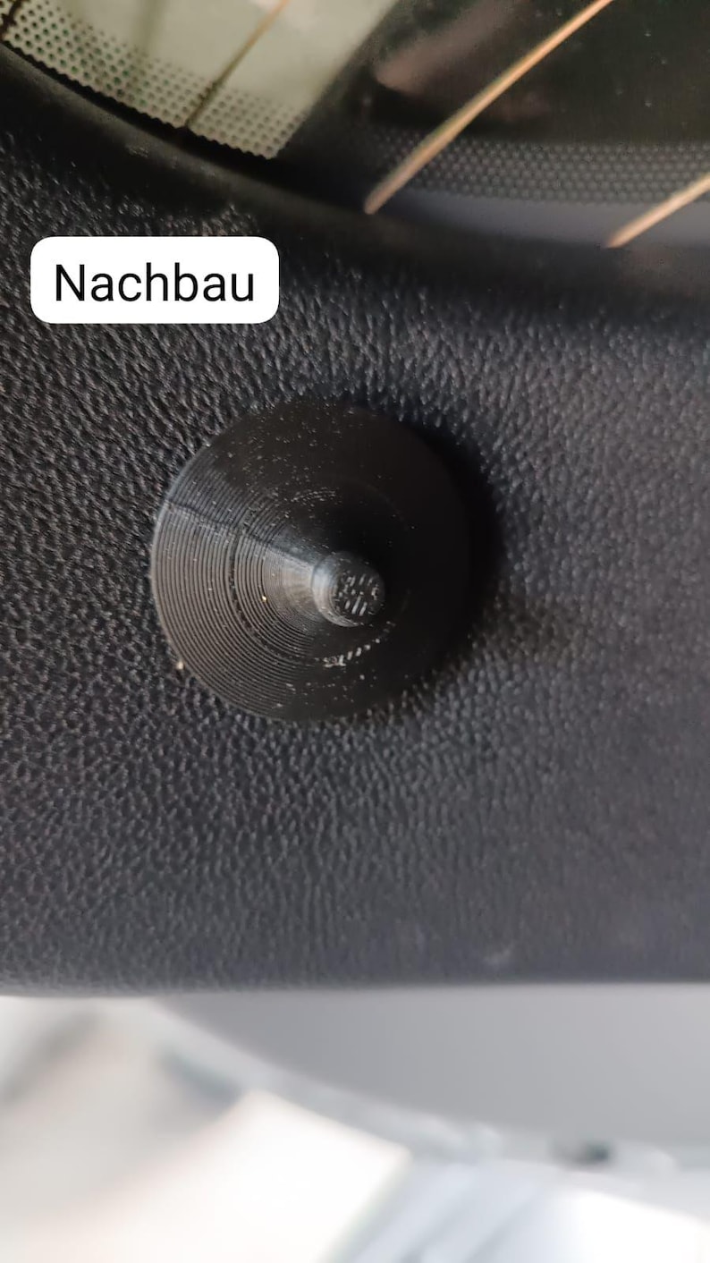 May include: A black, conical-shaped object with a circular base and a textured surface. The object is mounted on a black, textured surface. The word "Nachbau" is in a white rectangle in the image.