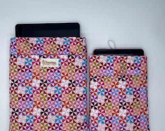 May include: Two fabric tablet and phone sleeves with a colorful geometric pattern in pink, purple, orange, and teal. The sleeves are rectangular with a pocket on the front. The larger sleeve holds a tablet, and the smaller sleeve holds a phone.
